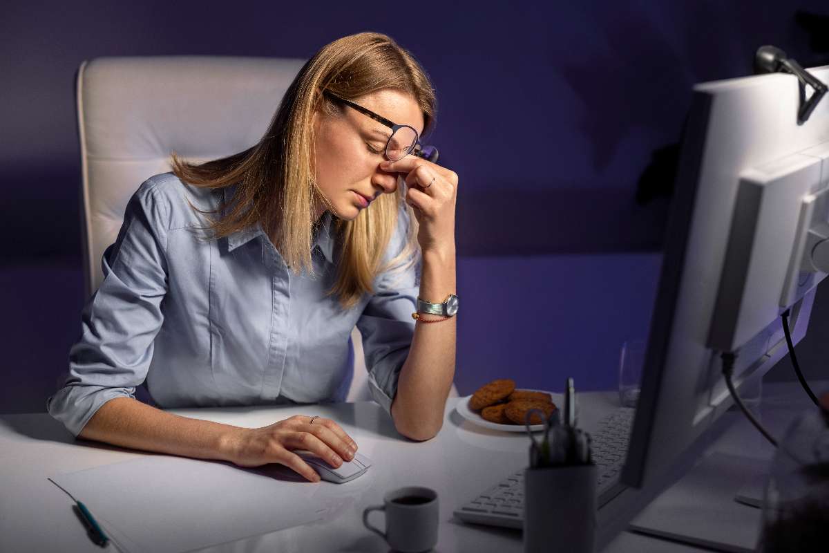 A woman working at night in front of a computer experiencing trouble in sleep