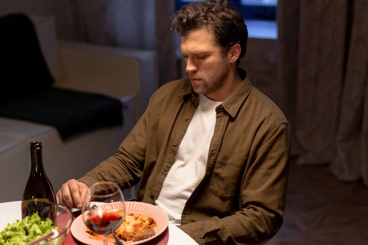 A man looking at a food plate with disinterest on his face towards eating