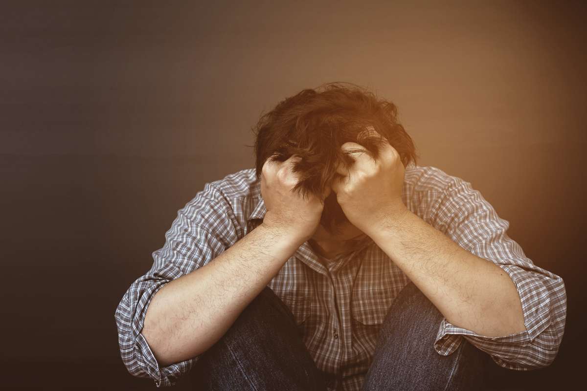 A man holding his head on stress that causes hair loss.