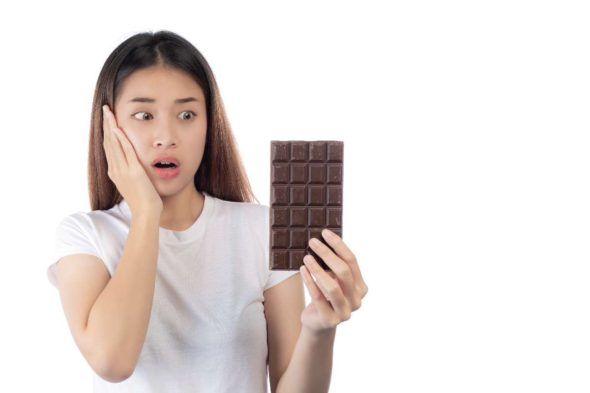 An Asian girl is holding chocolate and suffering from tooth cavities.