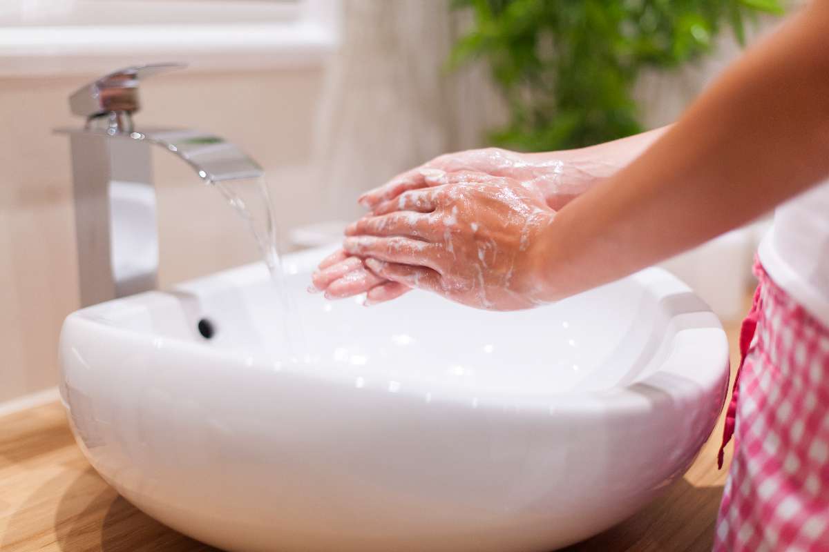 A person washing hands with soap to prevent common cold.