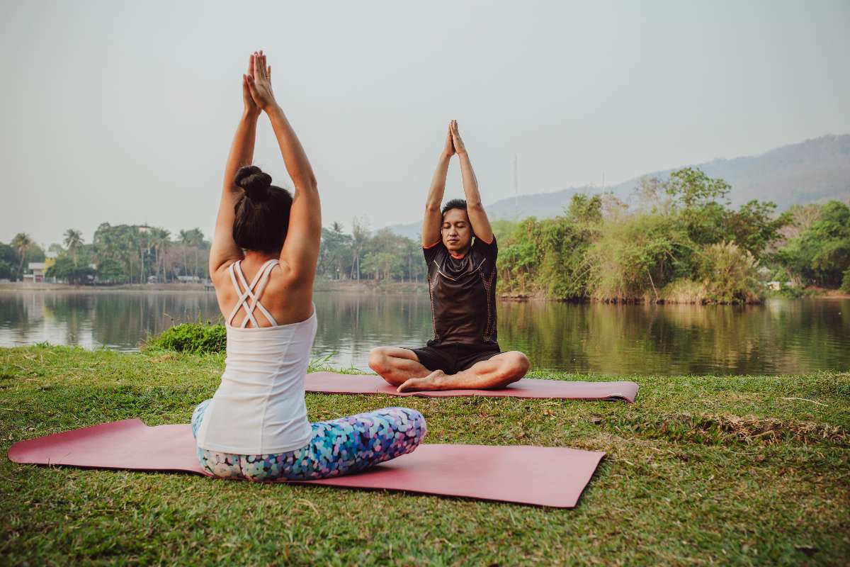 Two women practicing yoga in nature to remove stress.